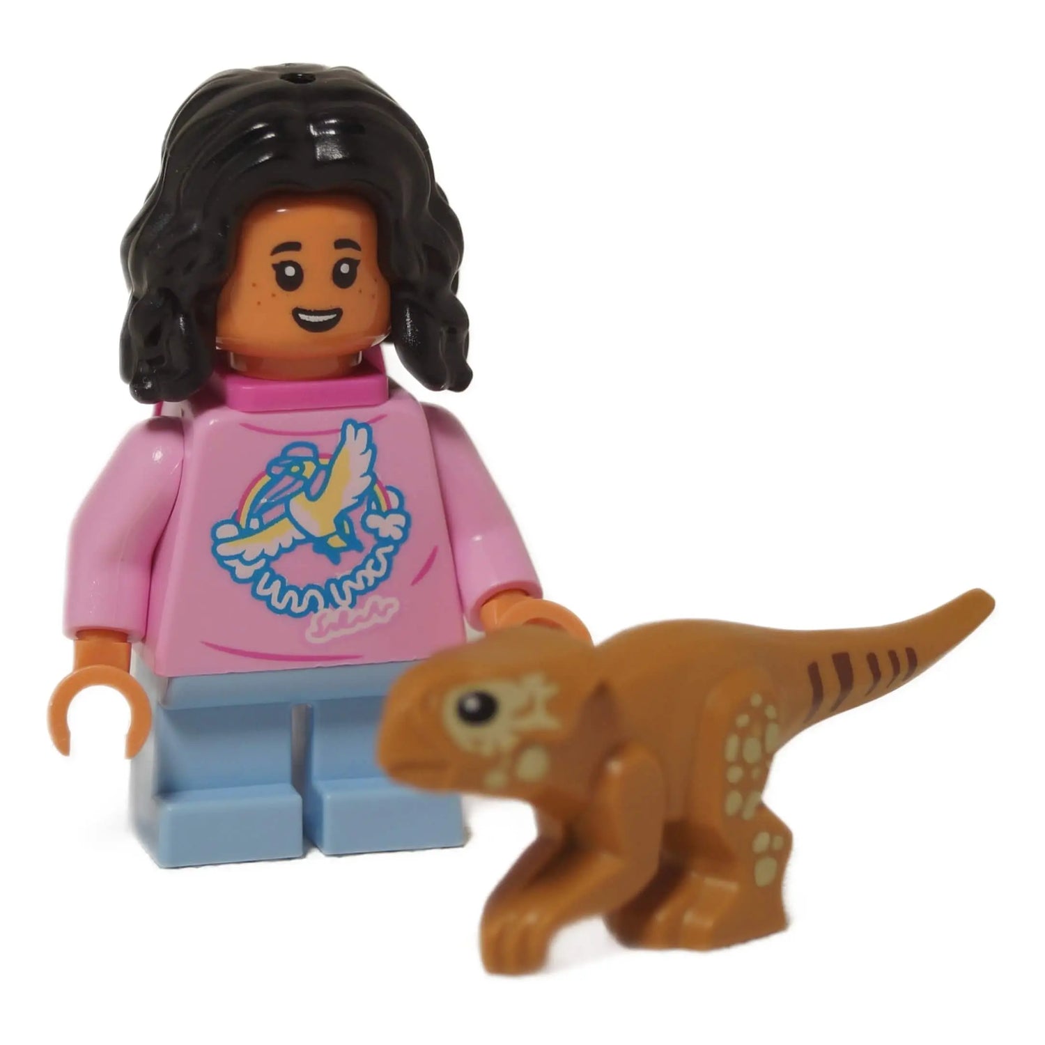 LEGO® Isabella Delgado minifigure from Jurassic World Rebirth with black curly hair, pink dove-print shirt, and light blue legs, posed next to a baby Aquilops dinosaur – part of the Rebirth minifigures collection.