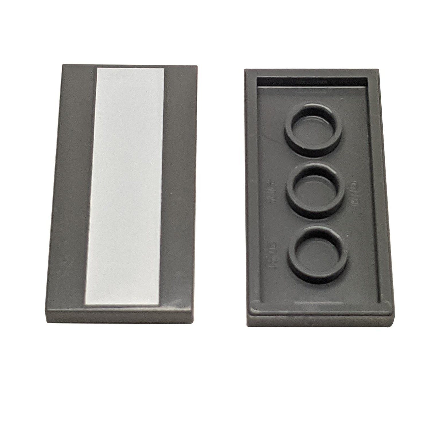 Two dark gray LEGO Tile 2x4 pieces (87079); one showing the smooth top with a vertical white stripe.