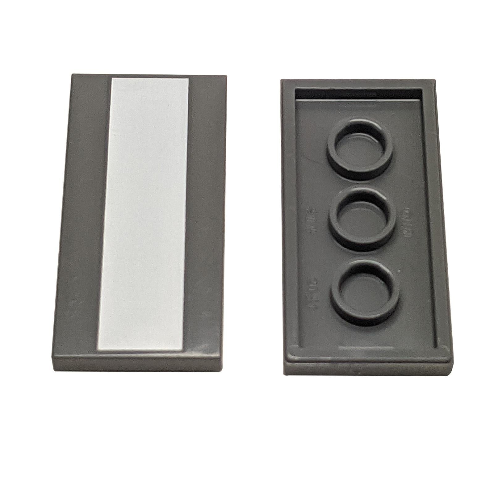 Two dark gray LEGO Tile 2x4 pieces (87079); one showing the smooth top with a vertical white stripe.