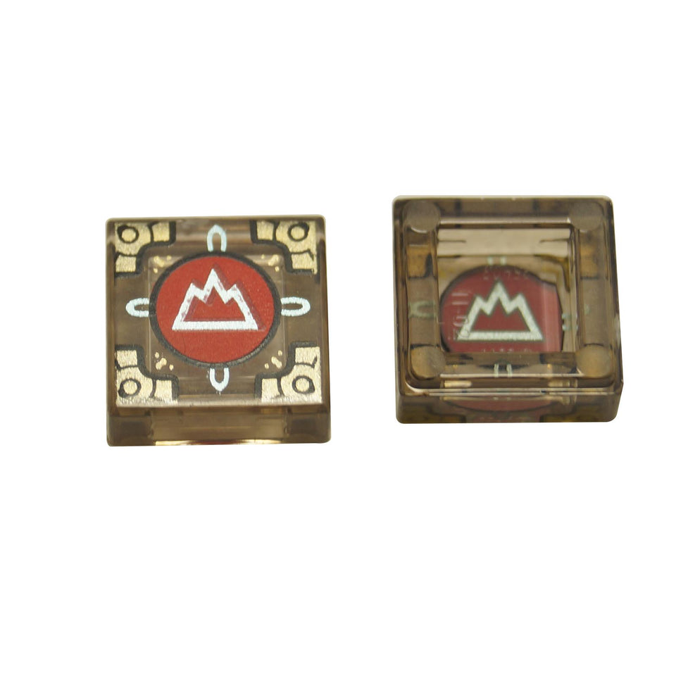 Two views of a LEGO trans-brown 1x1 tile with a metallic light blue mountain symbol on a red circle and gold corners, part of the Dungeons & Dragons Cubic Gate set.