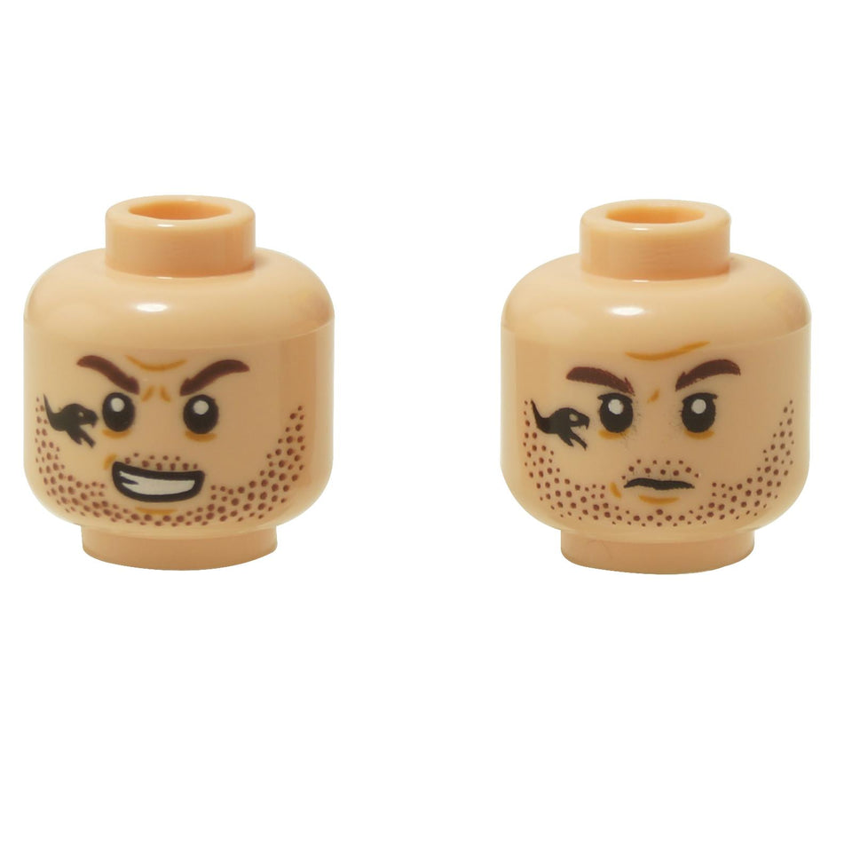 Front and alternate side views of the LEGO® minifigure head (3626pb3023) featuring dual expressions — a confident grin and an angry face — both with stubble and a distinctive black snake tattoo on the left cheek.