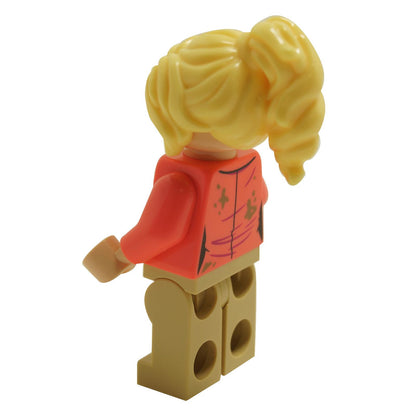 Side view of LEGO® Jurassic World Dr. Ellie Sattler minifigure with coral shirt printed with dark tan dirt spots and ponytail hairstyle
