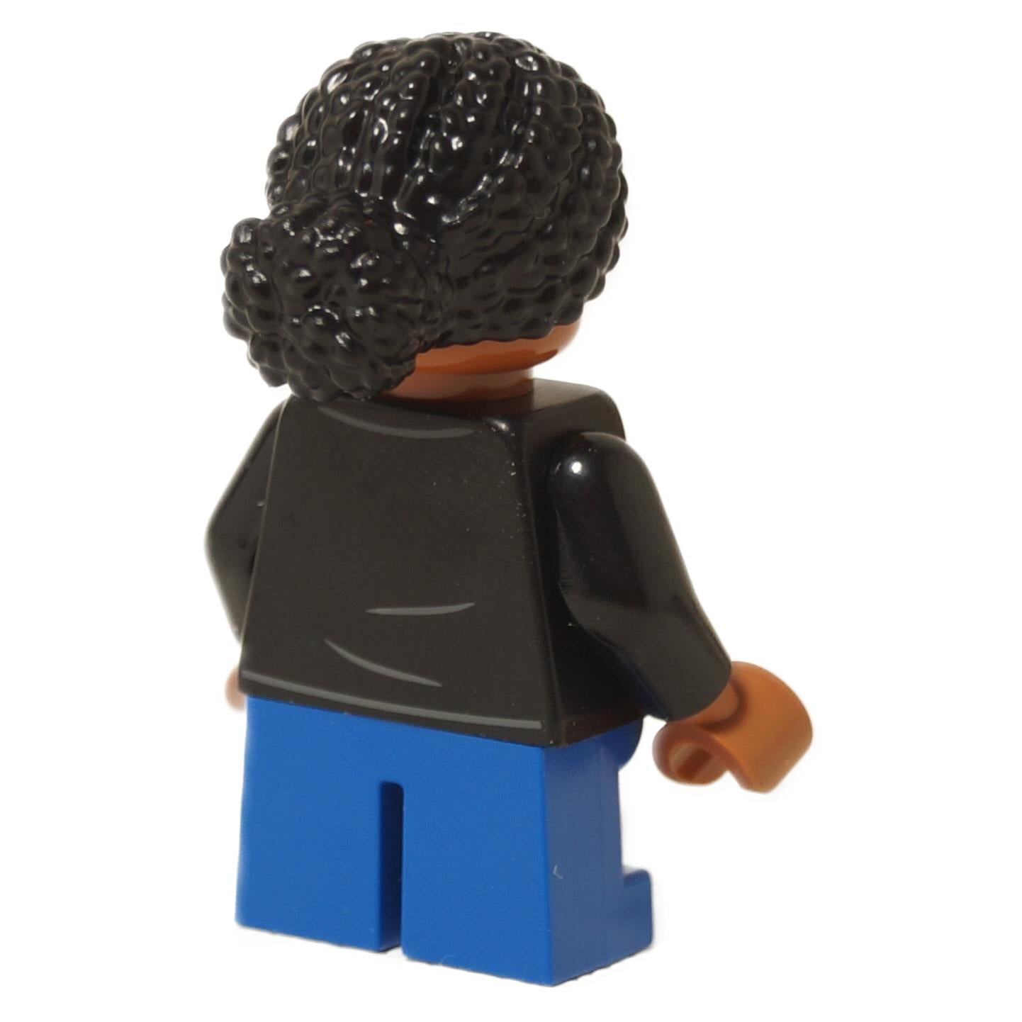 LEGO® Junior Paleontologist girl minifigure with black Jurassic Park logo shirt, blue short legs, and black braided hair, back profile view
