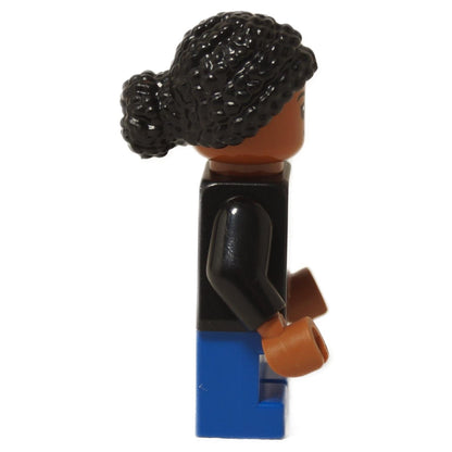 LEGO® Junior Paleontologist girl minifigure with black Jurassic Park logo shirt, blue short legs, and black braided hair, side profile view