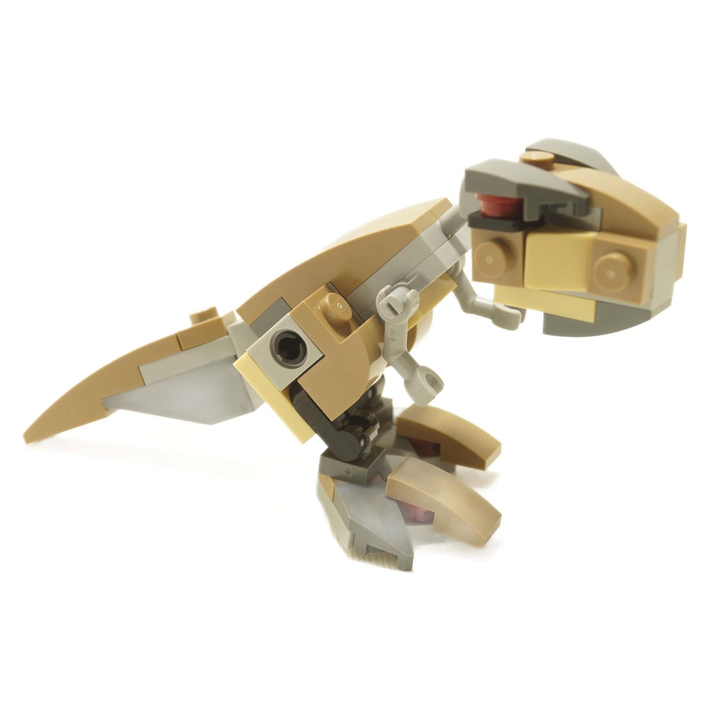 A small, brick-built model of a Tyrannosaurus Rex, constructed from beige and gray LEGO-like blocks.