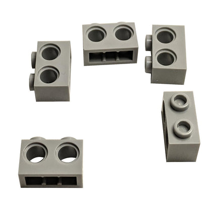 Five grey Technic Brick 1 x 2 with Holes 32000 from various angles.